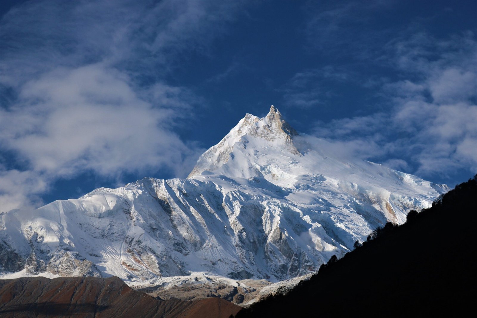 Breathtaking view of snow-covered Mount Manaslu under a clear blue sky, showcasing Himalayan grandeur.